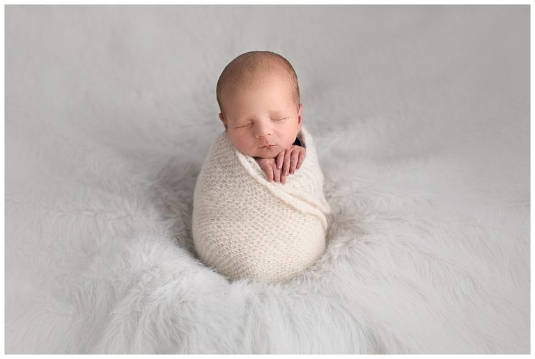 Studio newborn boy portrait photography with cream swaddle blanket. 