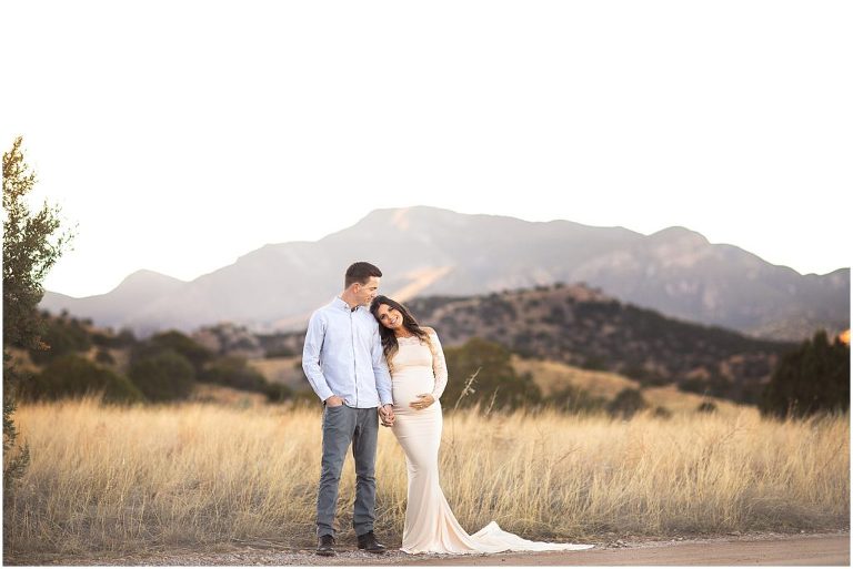 Maternity session with new mom and dad in Sierra Vista with mountain views. Mom in cream lace dress.